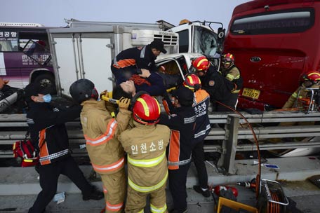 Firefighters rescue an injured man from a damaged vehicle on Yeongjong Bridge in Incheon