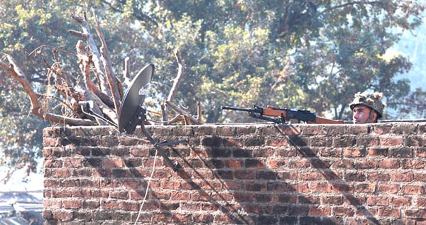 An Indian army soldier looks at an Indian air force chopper on a reconnaissance mission, as he takes position on a rooftop of a building outside the Indian airbase in Pathankot, 430 kilometers (267 miles) north of New Delhi, India, Saturday, Jan. 2, 2016. At least four gunmen entered an Indian air force base near the border with Pakistan on Saturday morning and exchanged fire with security forces, leaving two of them dead, officials said. (AP Photo/Channi Anand)
