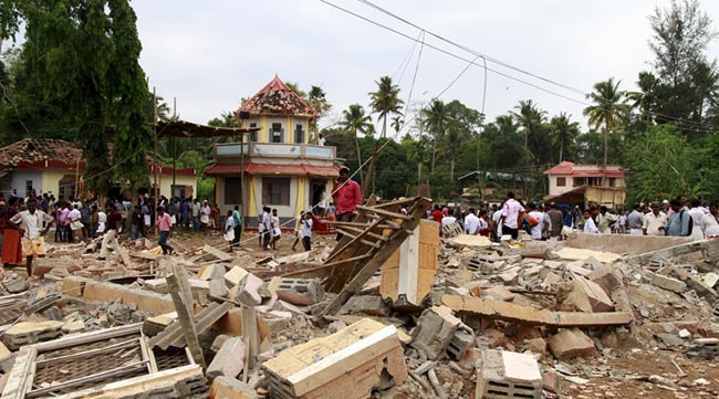 People walk past debris after a fire broke out at a temple in Kollam in the southern state of Kerala, India, April 10, 2016. A huge fire swept through a temple in India's southern Kerala state early on Sunday (April 10), killing nearly 80 people and injuring over 200 gathered for a fireworks display to mark the start of the local Hindu new year. REUTERS/Sivaram V