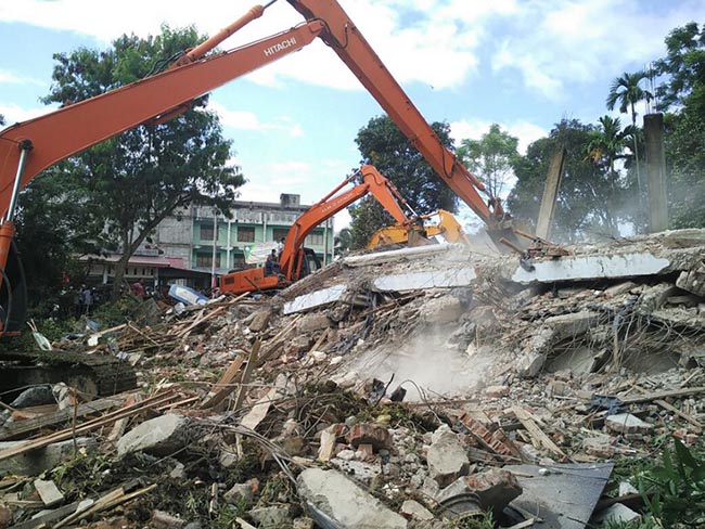 Indonesian search and rescue personnel work to rescue people trapped under the rubble of a collapsed building following an earthquake in Pidie, Aceh province on December 7, 2016.   At least 18 people died and dozens were feared trapped in rubble after a strong earthquake struck off Aceh province on Indonesia's Sumatra island on December 7, officials said. / AFP PHOTO / CHAIDEER MAHYUDDIN